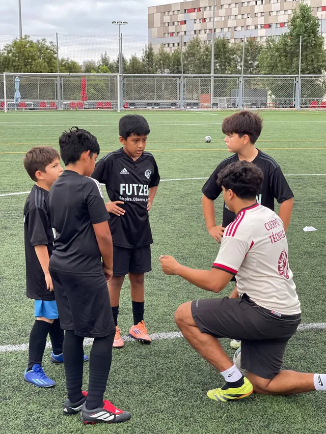 Un entrenador de FUTZEN, de rodillas, habla con cuatro niños
